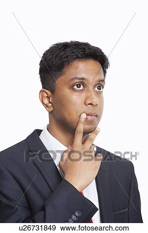 Contemplative young Asian businessman with hand on chin against white background View Large Photo Image Stock Photo - Contemplative young Asian businessman with hand on chin against white background. Fotosearch