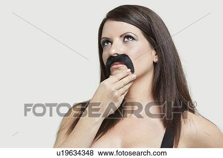 Contemplative young woman with a fake mustache looking up over gray background View Large Photo Image Stock Photo - Contemplative young woman with a fake mustache looking up over gray background. Fotosearch
