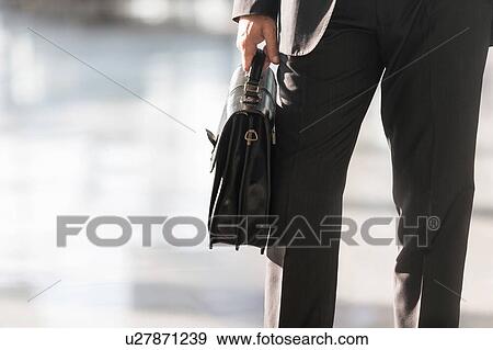 Cropped image of businessman holding briefcase bag in airport View Large Photo Image Stock Photo - Cropped image of businessman holding briefcase bag in airport. Fotosearch