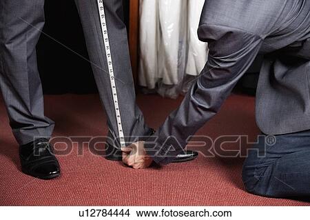 Cropped image of tailor measuring man's trouser in store View Large Photo Image Picture - Cropped image of tailor measuring man's trouser in store. Fotosearch