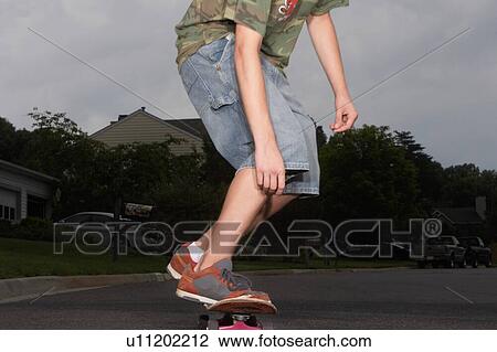 Stock Image - Cropped photo of kid riding skateboard. Fotosearch