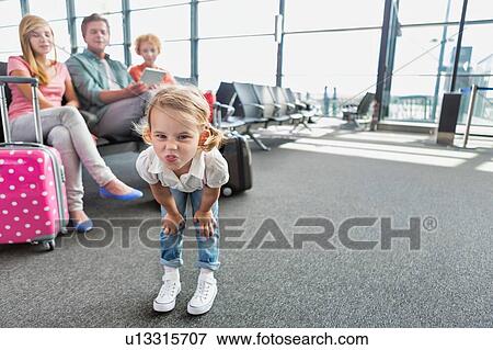 Cute little girl playing and making funny face in airport while waiting for boarding View Large Photo Image Stock Photo - Cute little girl playing and making funny face in airport while waiting for boarding. Fotosearch