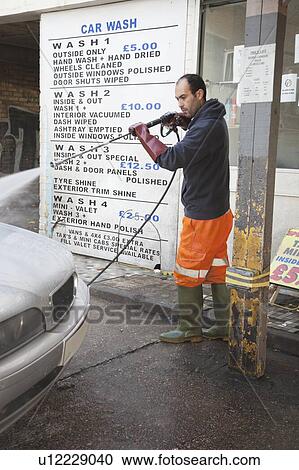 Stock Image - Employee washing vehicle at car wash. Fotosearch
