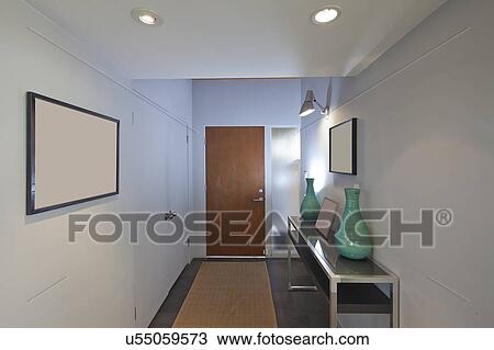 Stock Image - Entry with paintings and side table. Fotosearch