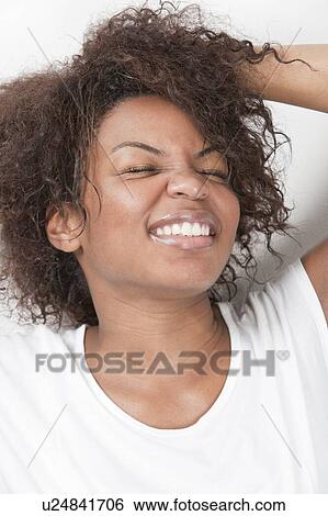 Excited young African American woman with hands in hair smiling against white background View Large Photo Image Stock Photograph - Excited young African American woman with hands in hair smiling against white background. Fotosearch