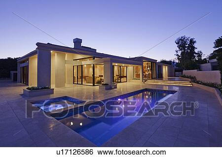 Stock Photograph - Exterior of modern home with swimming pool at dusk. Fotosearch