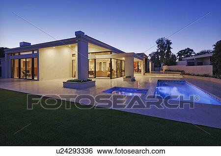 Stock Photograph - Exterior of modern home with swimming pool at dusk. Fotosearch