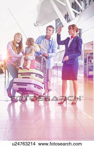 Picture - Family on holiday asking for assistance with airport staff in airport with lens flare in background. Fotosearch