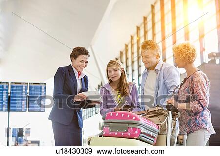 Family on holiday asking for assistance with airport staff in airport with lens flare in background View Large Photo Image Stock Photo - Family on holiday asking for assistance with airport staff in airport with lens flare in background. Fotosearch