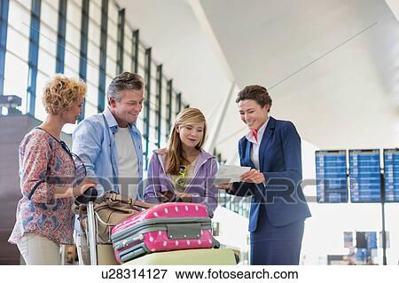 Stock Photo - Family on holiday asking for assistance with airport staff in airport with lens flare in background. Fotosearch