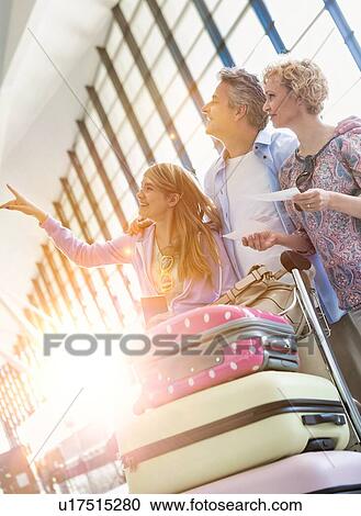 Stock Image - Family on holiday looking at their flights on monitor in airport. Fotosearch