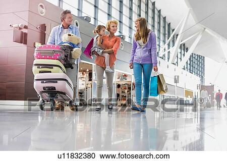 Stock Image - Family on holiday trip walking in airport with lens flare. Fotosearch
