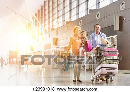 Family on holiday trip walking in airport with lens flare View Large Photo Image Stock Photo - Family on holiday trip walking in airport with lens flare. Fotosearch