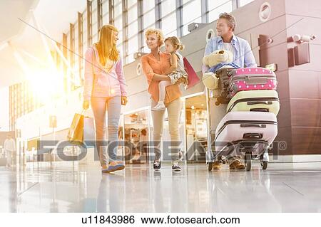 Stock Photograph - Family on holiday trip walking in airport with lens flare. Fotosearch