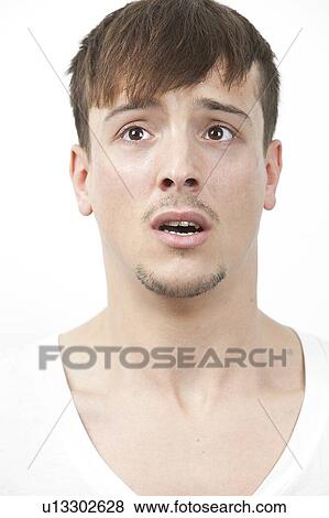 Stock Photo - Fearful young man looking away over white background. Fotosearch
