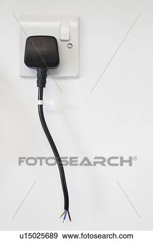 Stock Photo - Frayed electrical cord with outlet attached on white wall. Fotosearch