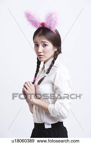 Frightened young woman with bunny ears against white background View Large Photo Image Stock Photo - Frightened young woman with bunny ears against white background. Fotosearch