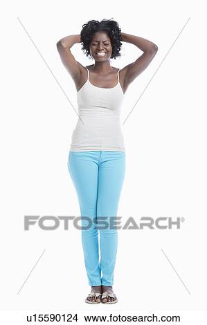 Picture - Frustrated young woman with hands behind head standing against white background. Fotosearch