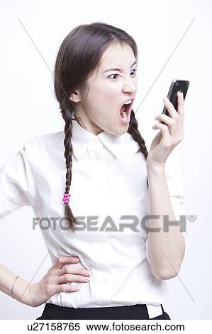 Furious young woman screaming into her cell phone against white background View Large Photo Image Stock Photography - Furious young woman screaming into her cell phone against white background. Fotosearch