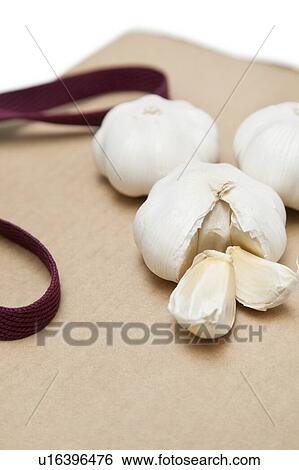 Garlic with separated pieces on wooden chopping board View Large Photo Image Stock Photograph - Garlic with separated pieces on wooden chopping board. Fotosearch