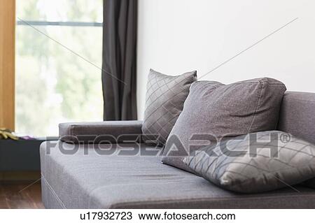 Stock Image - Gray sofa with cushions in house. Fotosearch