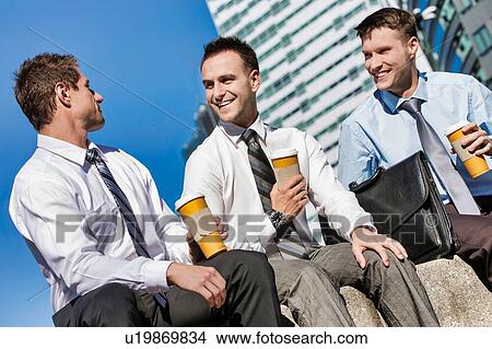 Picture - Group of colleagues sitting and talking while drinking coffee after work. Fotosearch