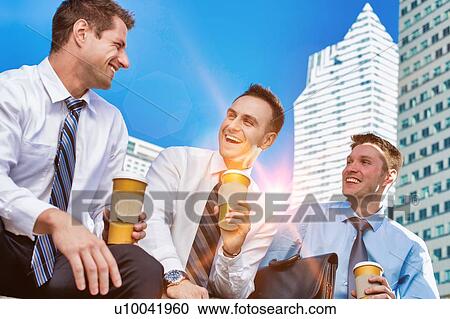 Stock Image - Group of colleagues sitting and talking while drinking coffee after work. Fotosearch