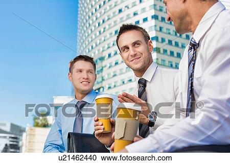 Group of colleagues sitting and talking while drinking coffee after work View Large Photo Image Stock Image - Group of colleagues sitting and talking while drinking coffee after work. Fotosearch