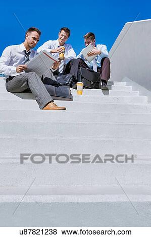 Stock Photo - Group of handsome business colleagues sitting on stairs . Fotosearch