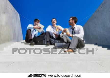 Group of handsome businessman sitting on stairs while talking during break View Large Photo Image Stock Photograph - Group of handsome businessman sitting on stairs while talking during break . Fotosearch