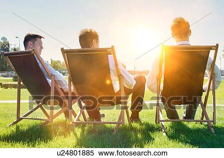 Group of handsome businessmen relaxing and talking about life while sitting on folding chair at park View Large Photo Image Stock Photography - Group of handsome businessmen relaxing and talking about life while sitting on folding chair at park. Fotosearch
