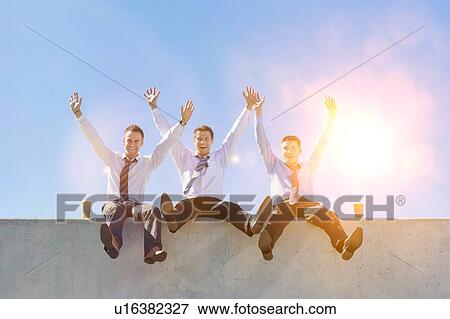 Stock Photo - Group of handsome businessmen sitting while having fun in office rooftop. Fotosearch