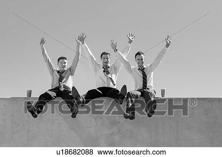 Stock Photo - Group of handsome businessmen sitting while having fun in office rooftop. Fotosearch
