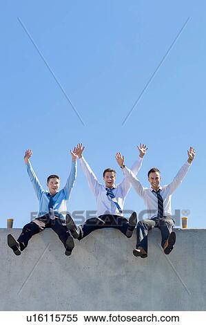 Stock Photography - Group of handsome businessmen sitting while having fun in office rooftop. Fotosearch