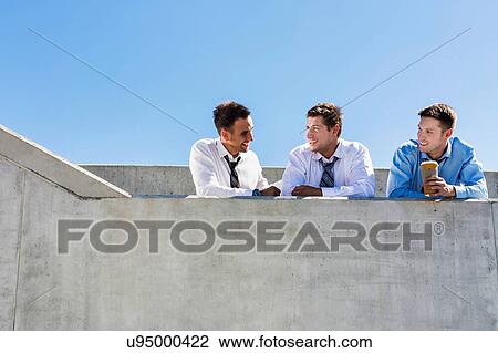 Group of handsome businessmen discussing plans in office rooftop during break View Large Photo Image Stock Image - Group of handsome businessmen discussing plans in office rooftop during break. Fotosearch