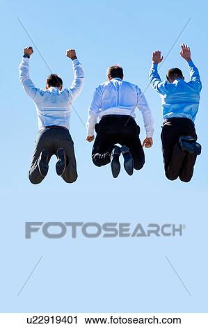 Stock Image - Group of mature businessmen jumping on office rooftop. Fotosearch