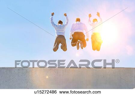 Stock Photograph - Group of mature businessmen jumping on office rooftop. Fotosearch