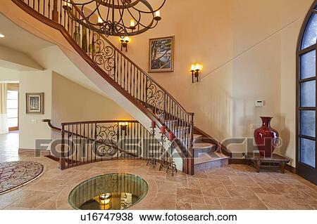 Stock Photo - Hallway interior with stairs and chandelier in luxury villa. Fotosearch