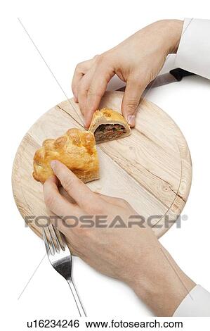 Hands holding Cornish pastry cut into two pieces on wooden plate over white background View Large Photo Image Stock Photograph - Hands holding Cornish pastry cut into two pieces on wooden plate over white background. Fotosearch