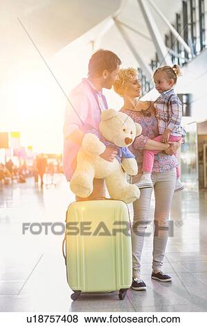 Stock Photo - Happy family on a holiday arriving at the airport with lens flare. Fotosearch