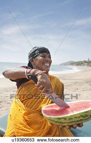 Happy mature Indian woman cutting watermelon at Vagator Beach View Large Photo Image Stock Image - Happy mature Indian woman cutting watermelon at Vagator Beach. Fotosearch