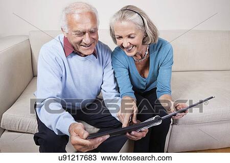 Happy senior couple looking at spiral book View Large Photo Image Stock Image - Happy senior couple looking at spiral book. Fotosearch