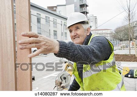 Stock Photo - Happy senior male worker at working at construction site. Fotosearch
