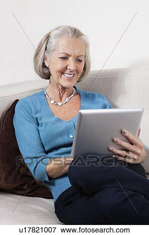 Stock Photo - Happy senior woman using digital tablet at home. Fotosearch