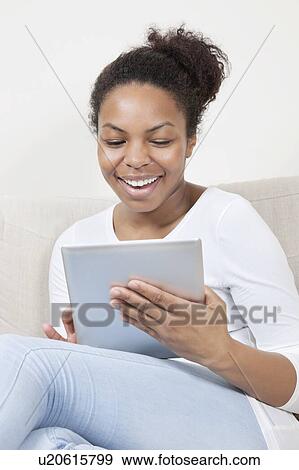 Stock Photo - Happy young African American woman using tablet PC. Fotosearch