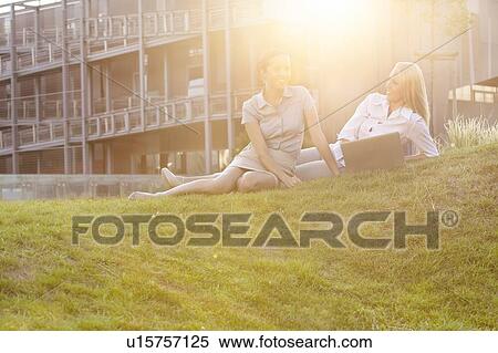 Happy young businesswomen with laptop on office lawn View Large Photo Image Stock Photography - Happy young businesswomen with laptop on office lawn. Fotosearch