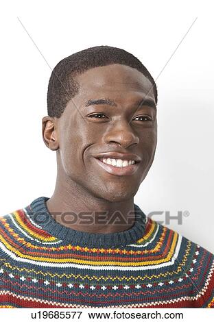 Stock Photo - Happy young man in knitwear looking away over white background. Fotosearch