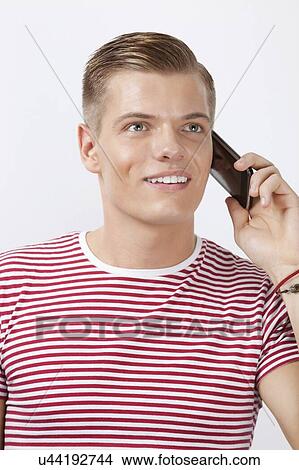 Happy young man using cell phone against white background View Large Photo Image Picture - Happy young man using cell phone against white background. Fotosearch