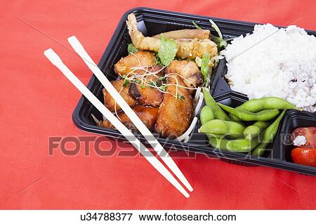 Stock Photo - Healthy food served in tray with chopsticks over red background. Fotosearch