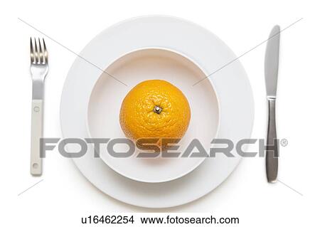 Picture - High angle view of an orange in dish with fork and knife over white background. Fotosearch